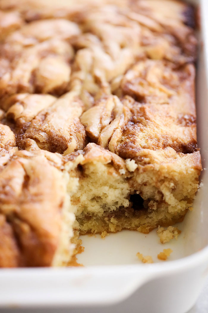 Cinnamon Roll Cake in a white baking dish with a slice removed.