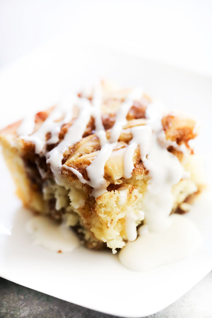 Slice of Cinnamon Roll Cake on a white plate with vanilla glaze drizzled overtop.