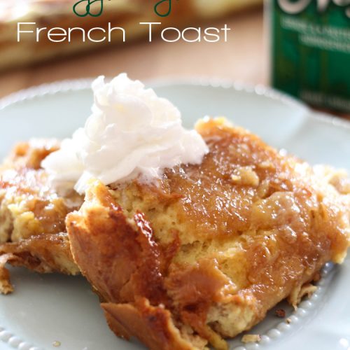 Two slices of Overnight Egg Nog French Toast served on a plate with a swirl of whipped cream atop.