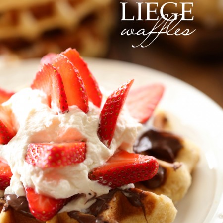 Liege Waffles on white plate topped with Nutella, whipped cream and strawberries
