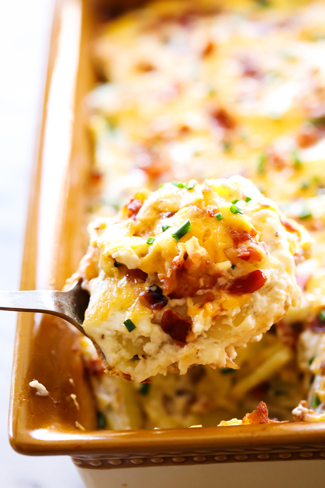 Loaded Scalloped Potatoes in baking dish with a spoon scooping some out.