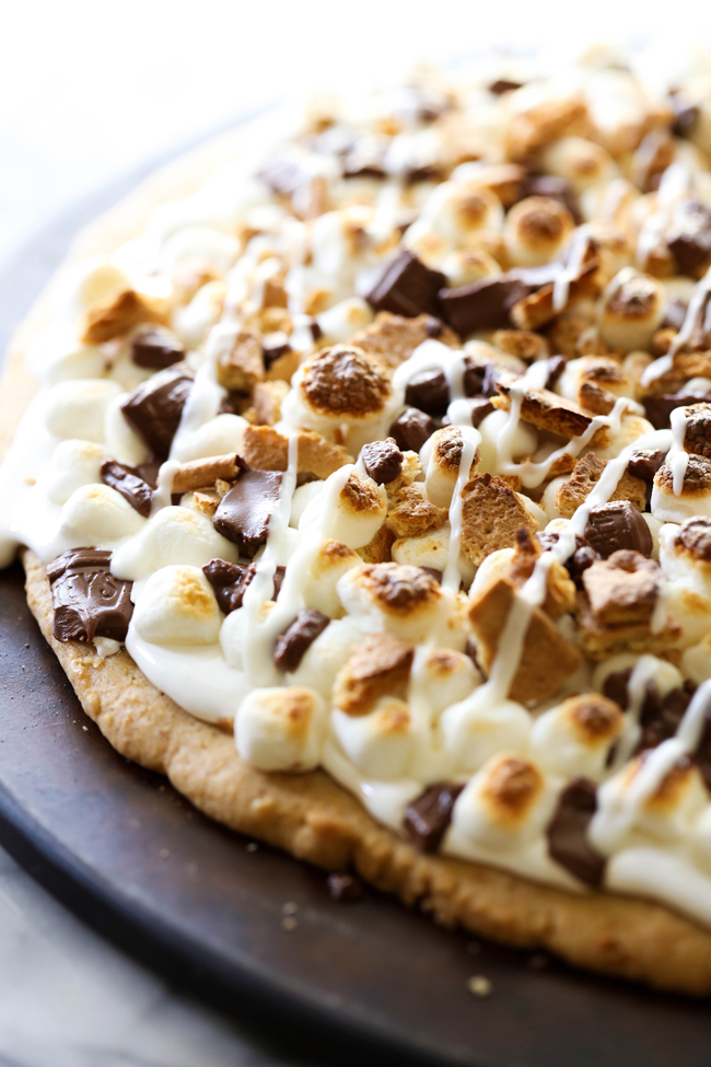 This S'more Cookie Pizza begins with a graham cracker cookie that is topped with marshmallow cream, mini marshmallows, chocolate and crushed graham crackers. It is a delicious, show-stopping dessert that is perfect for special occasions!