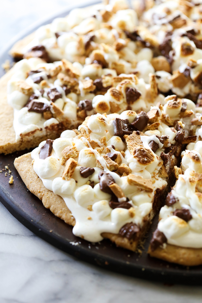 This S'more Cookie Pizza begins with a graham cracker cookie that is topped with marshmallow cream, mini marshmallows, chocolate and crushed graham crackers. It is a delicious, show-stopping dessert that is perfect for special occasions!