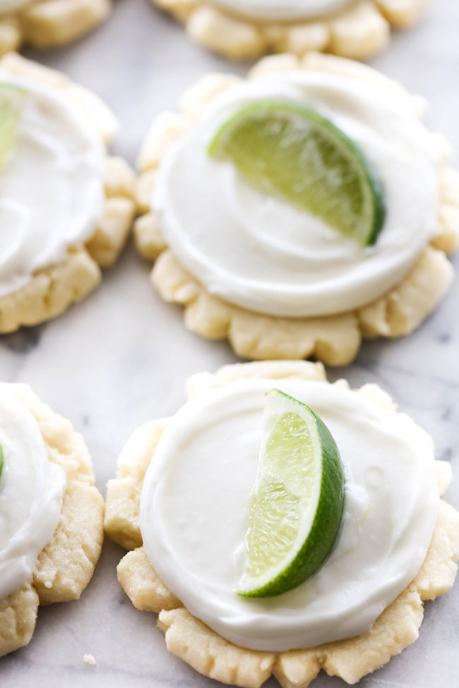 Coconut Lime Sugar Cookies with coconut lime frosting and garnished with a slice of lime.