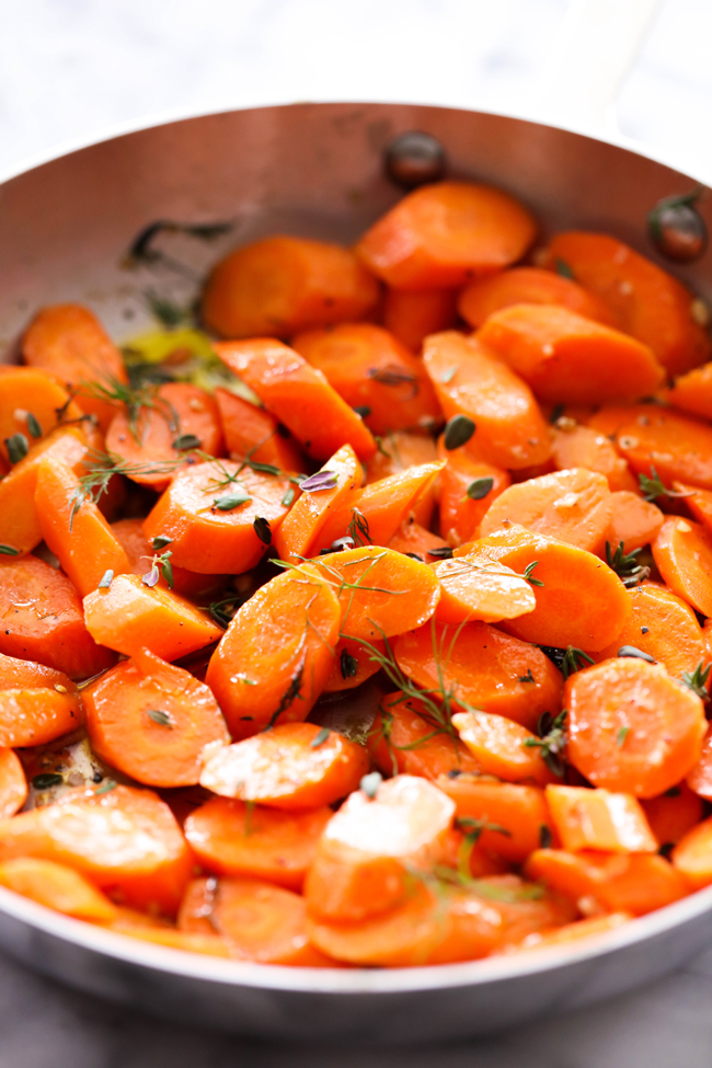 Garlic Butter Herb Carrots cut in slices in a stainless steel skillet.