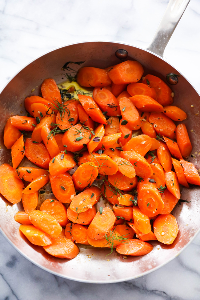 Overhead view of Garlic Butter Herb Carrots in a stainless steel skillet.