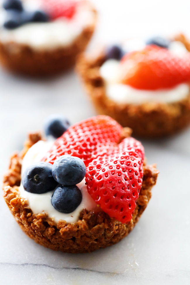 Mini Granola Yogurt Fruit Tarts made in a muffin pan and garnished with strawberry slices and blueberries.