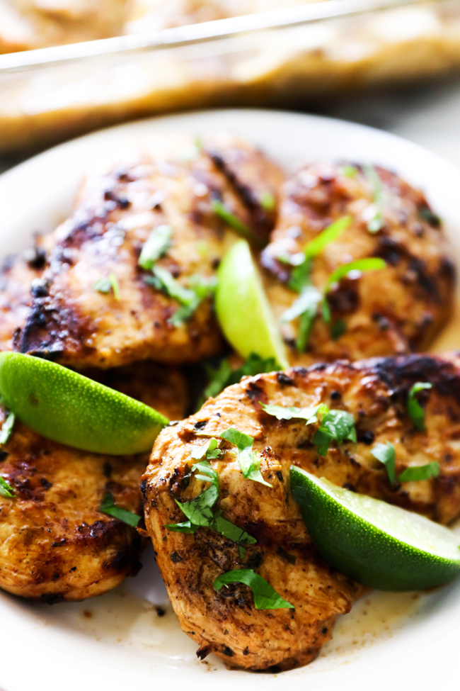 Grilled Southwest Chicken on white plate garnished with fresh chopped cilantro and three slices of lime.
