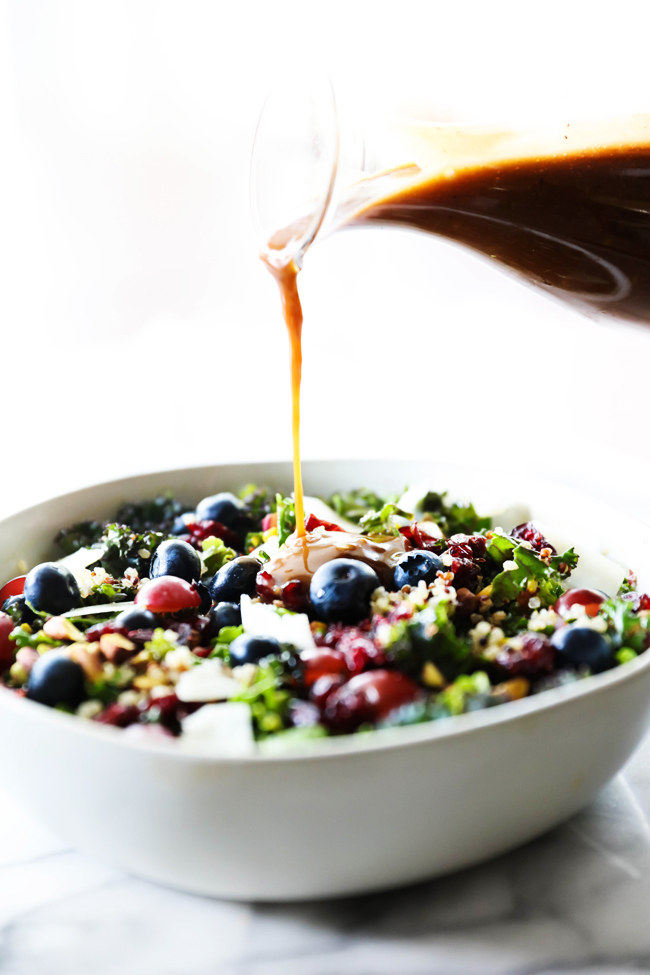 Balsamic Dressing drizzling over Kale and Quinoa Salad in a white bowl.