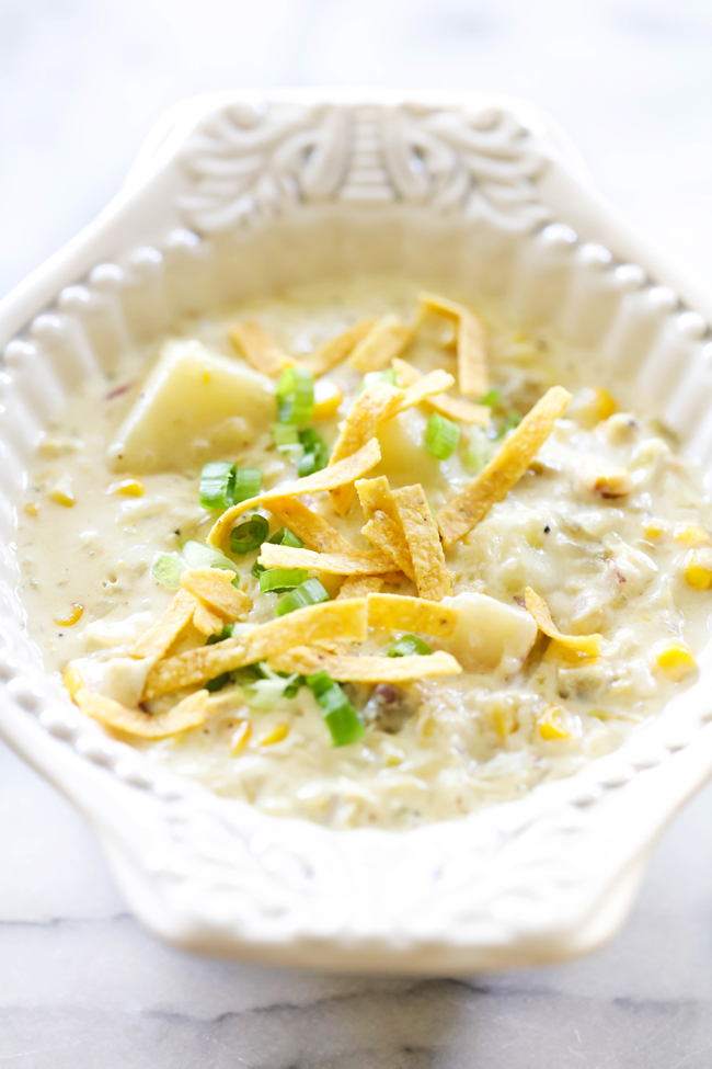 Green Chile Potato Soup in white bowl garnished with sliced green onions and tortilla chips.