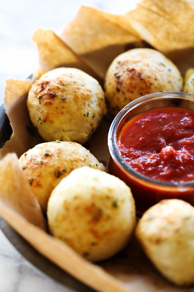 Pizza Stuffed Rolls in a brown paper lined metal serving tray surrounding a small container of marinara sauce.